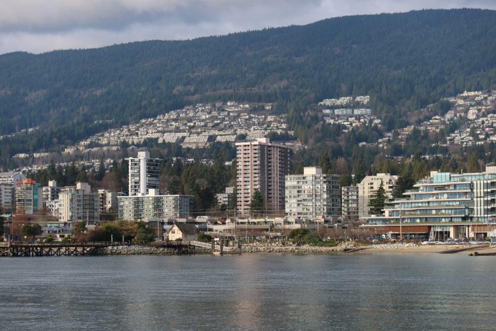 West Vancouver as seen from Ambleside Park in West Vancouver.  Houses (including Yuki's Piano Studio) in West Vancouver are situated on the side of the Coast Mountains.  Apartments and condominium towers are lined along the seawall of West Vancouver.